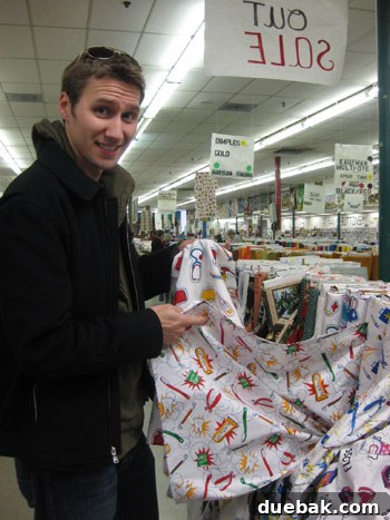 Man humorously posing with dental-themed fabric at Mary Jo's, highlighting the store's unique and extensive selection.