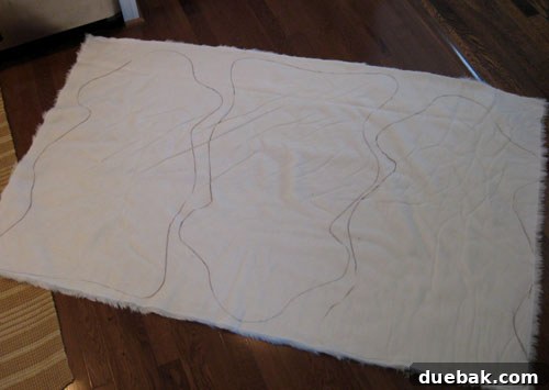 Faux Sheepskin Rug: The Finishing Touches 4 Close-up of a paper sheepskin template being traced onto the back of ivory faux fur fabric with a marker.