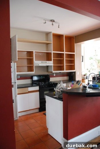 Dated kitchen before renovation with older cabinets and orange floor tiles.