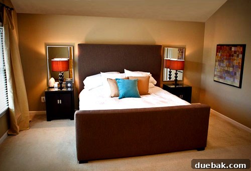 After: Transformed bedroom featuring vibrant aqua accents, striped slipper chairs, and modern art.