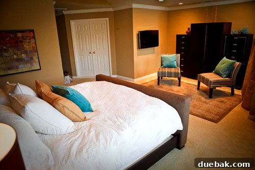 After: Cozy bedroom corner with a striped slipper chair, throw pillow, and a glimpse of the patterned rug.
