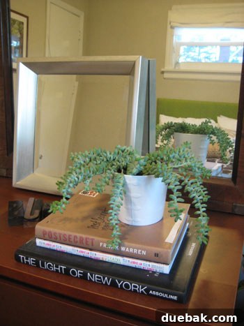 A simple yet elegant spring display featuring white ceramic vessels and fresh green potted plants on a natural wood surface.