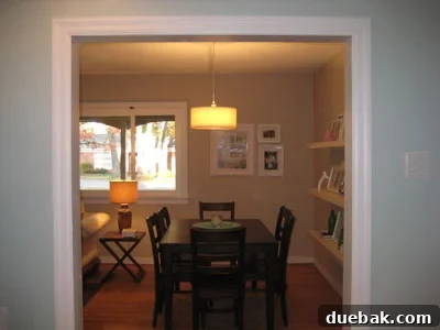 CB2 pendant light hanging over a dining table, seen from the kitchen, illuminating a modern dining area.