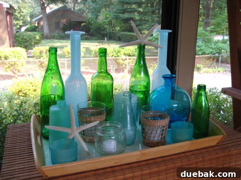 Grouping of recycled green wine bottles and colorful blue glass vases on a tray