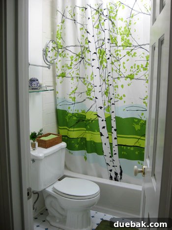 Step Inside This Exquisite City Residence 11 Bathroom with cheerful green accents, a printed shower curtain, and crisp white elements.