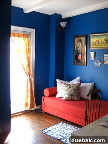 Step Inside This Exquisite City Residence 10 Guest bedroom slash office with a bold peacock blue wall, pomegranate daybed, and eclectic art.