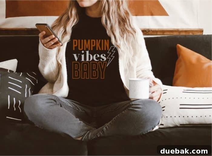 Woman wearing a black shirt that says 'Pumpkin Vibes Baby' in stylish typography.