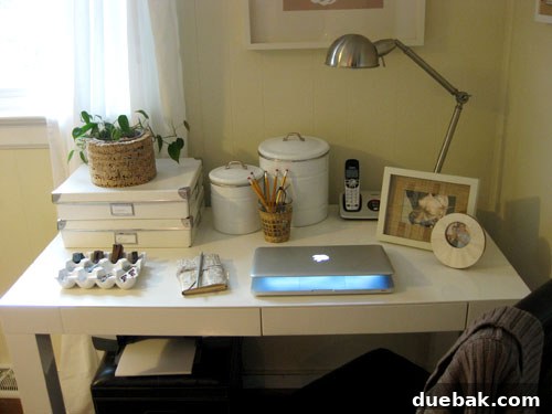 Close-up of natural-themed desk, showing the plant, woven cup, leather journal, and ceramic egg crate.
