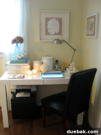 Home office desk decorated with beachy accents, including a blue vase, shells, and sea glass votives.