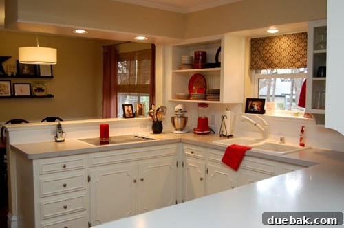 Transform Your Kitchen Without Breaking the Bank 6 Dining area seamlessly connected to the kitchen after partial wall removal, showcasing a modern pendant light, minimalist floating shelves, and cheerful red curtains, creating an inviting and cohesive space.