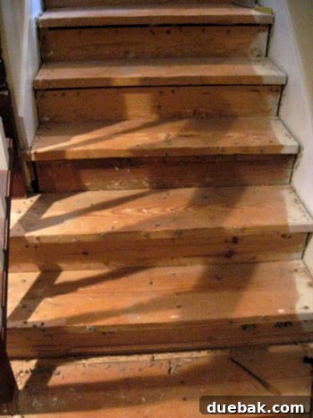 Old, heavily worn beige carpeted staircase before home renovation