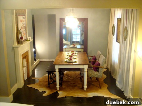 Elegant dining room with a faux fireplace, drop cloth curtains, and a stunning DIY mason jar chandelier.