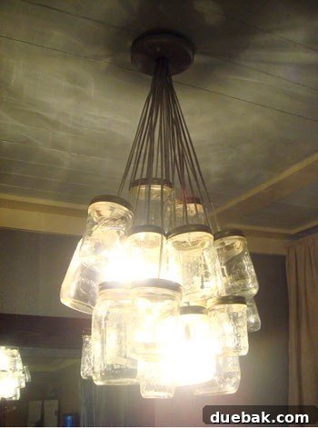 Close-up of Kara's stunning DIY mason jar chandelier, casting a warm glow in the dining room.