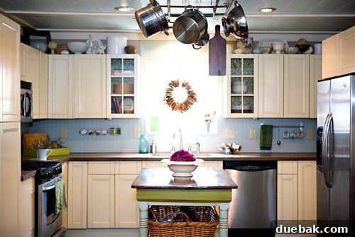 Modern kitchen with DIY concrete countertops, glass-front cabinets, and a unique pot rack made from reclaimed copper plumbing.