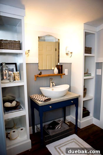 Transformed guest bathroom with hardwood floors, a repurposed desk vanity with concrete top, and custom built-ins.
