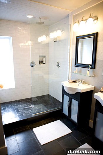 En-suite bathroom with white reflective tiles, a glass shower screen, and modern vanities for an open, airy feel.