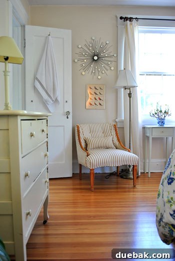 Bright & Beautiful Homes 14 Inviting guest bedroom featuring a beautifully reupholstered vintage armchair, a charming soft yellow dresser, and tasteful artwork, showcasing budget-friendly elegance.