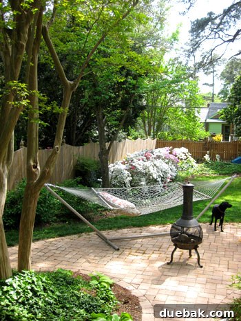 Bright & Beautiful Homes 15 Lush and inviting private backyard oasis featuring a comfortable hammock, a rustic chiminea, an expanded patio with an outdoor dining area, and plenty of space for relaxation.