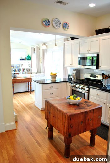 Bright & Beautiful Homes 8 Massive and character-rich butcher block island with stools, serving as a focal point in the open-concept kitchen, adding rustic charm to the elegant white and black design.