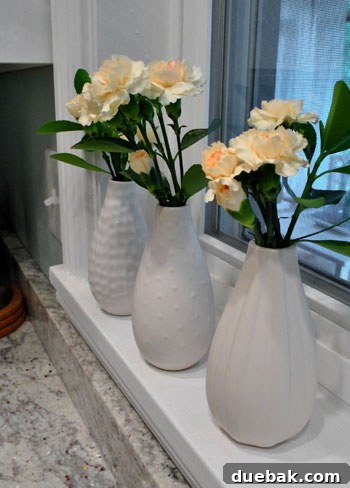 May Bloom Bonanza 3 Close-up of cream carnations and greenery in a white Ikea vase