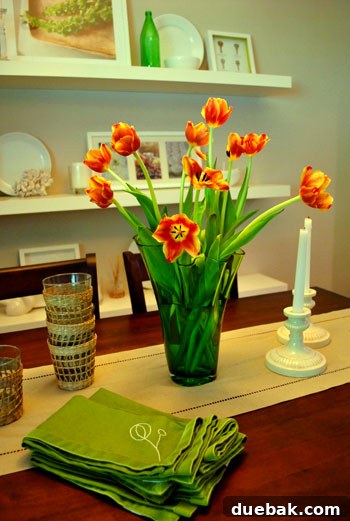 May Bloom Bonanza 8 Vibrant tulips in a green Crate & Barrel vase on a dining room table