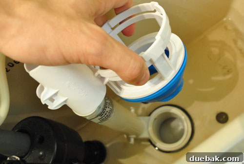 Upgrade Your Toilet with a Dual-Flush Kit 5 A hand sliding the base of a dual flush converter onto the toilet tank gasket, ensuring a tight seal.