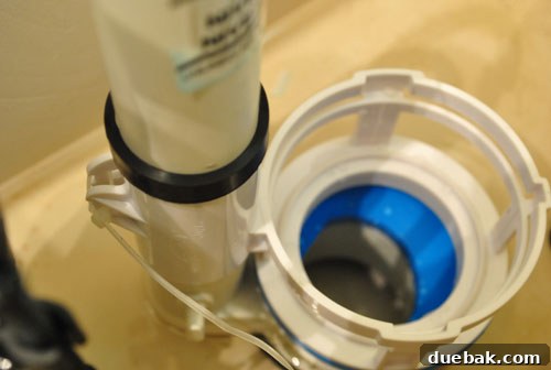 Upgrade Your Toilet with a Dual-Flush Kit 6 The dual flush converter base securely placed in the toilet tank, showing rubber band and zip-tie.