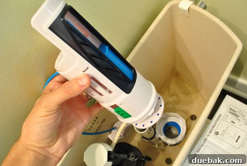 Upgrade Your Toilet with a Dual-Flush Kit 7 The main flush tower assembly being placed into the toilet tank for dual flush conversion, showing adjustable sliders.