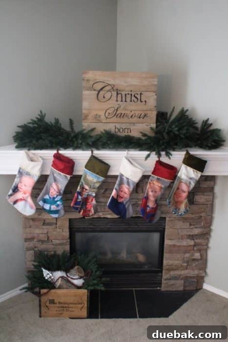 Stone corner fireplace with faux stone decorated for Christmas with greenery and a wood pallet sign.