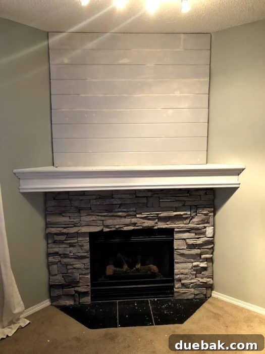Stone corner fireplace with whitewashed stone. Process photo of adding shiplap to fill in the awkward space above the TV.