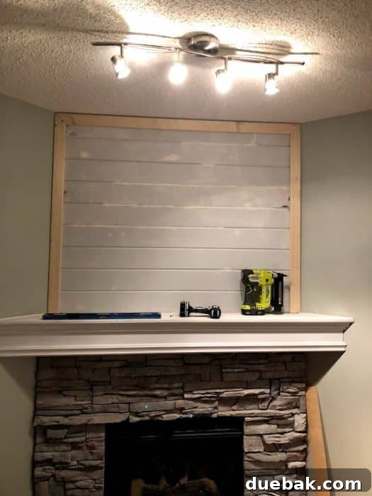 Stone corner fireplace with whitewashed stone. Process photo of adding shiplap to fill in the awkward space above the TV.