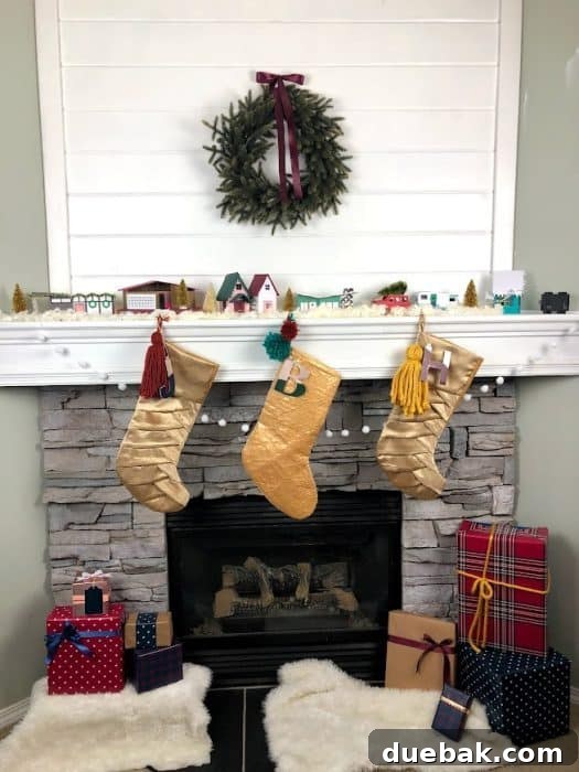 Stone corner fireplace with whitewashed stone and shiplap to fill in the awkward space above the TV. Decorated for Christmas with a wreath, stockings, and a midcentury modern paper house village.