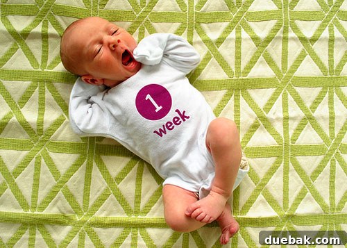 A baby lying on a colorful patterned blanket for a weekly photo shoot.