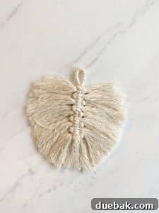 A process photo showing how to trim a macrame feather. The ropes have been brushed out and need to be trimmed.