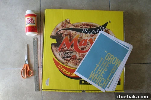 A collection of crafting supplies for the pizza box art project, including Mod Podge, laser prints, scissors, and a brush.