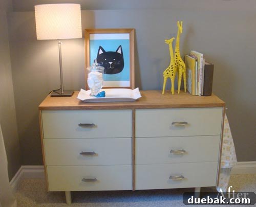 The dresser in its newly transformed state, showcasing the two-tone wood and soft green paint with new hardware.