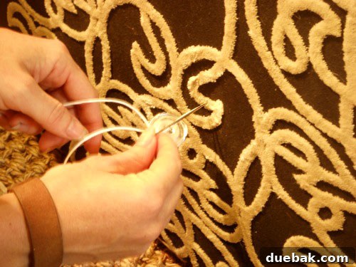 Handcraft Your Perfect Ottoman 10 Tufting button threaded onto the needle on the ottoman surface