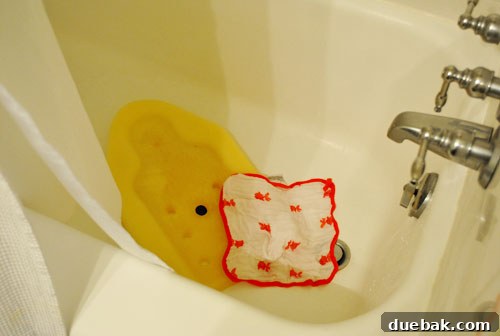 Taming the Baby Clutter 6 A simple yellow foam baby bath mat resting inside a bathroom sink, ready for bath time, highlighting practical baby care solutions.