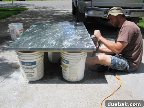 Crafting a Steel and Marble Dining Table 4 Ben polishing the edges of a dark greenish-black marble slab with a grinder