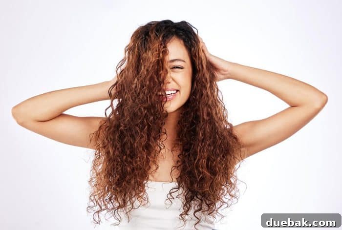 Portrait of a beautiful young woman showing off her natural curly hair against a white background.
