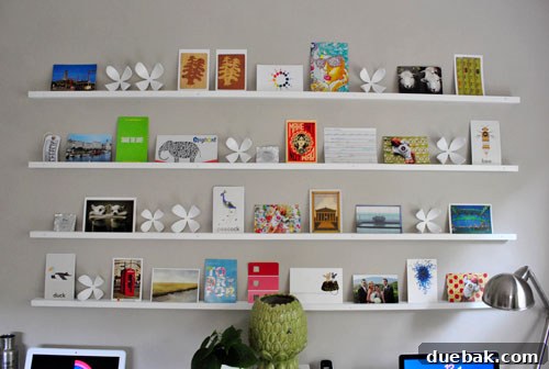 Wall of rotating postcard art on custom shelves