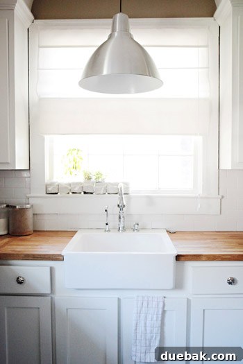 The Thousand Dollar Kitchen That Looks Like a Million 4 Detailed shot of the renovated kitchen showing new white sink, modern faucet, and classic white subway tile backsplash.