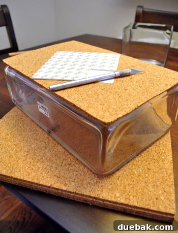 Transform Cork Into Chic Fabric Vases 5 Close-up of a hand using an Exacto knife to precisely cut cork squares to fit a glass vase, a key step in DIY cork vase creation.