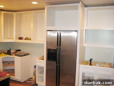 Our Kitchen Cabinets Channel Mariah Carey 2 Kitchen cabinet installation progress showing new white cabinets and a space for a built-in refrigerator.