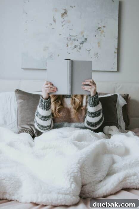 Woman relaxing in bed, engrossed in a book, highlighting a peaceful reading moment.
