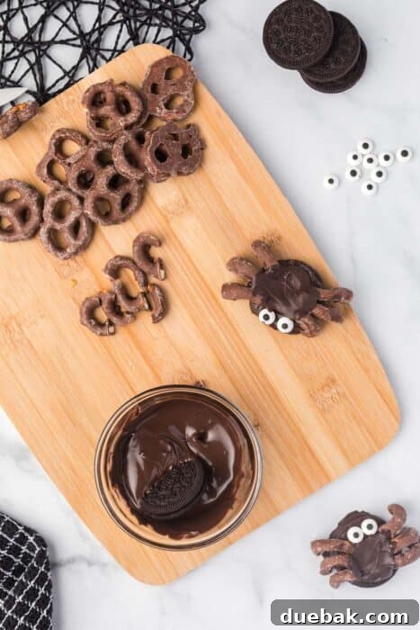 Simple Spooky Spider Treats for Halloween 3 A child's hand holding a spoon, ready to dip an Oreo into a small bowl of melted chocolate, emphasizing kid involvement.
