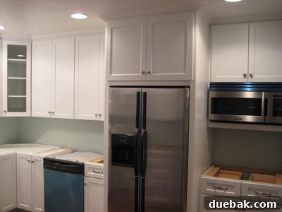 Cabinets Are In Our Kitchen's Taking Shape 3 Right side of kitchen, highlighting glass corner cabinet and protective plastic on appliances