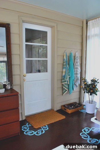 Colorful beach towels on hooks and a beloved DIY faux orange tree near a shoe basket