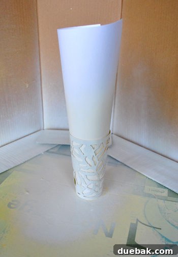 A white-painted metal cup, with the yellow interior visibly protected by a rolled piece of white paper still inside, showcasing the progress.