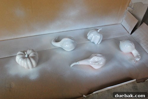 Gourd-geous Autumn Crafts 3 A hand holding a white faux gourd, freshly spray-painted with glossy white paint.